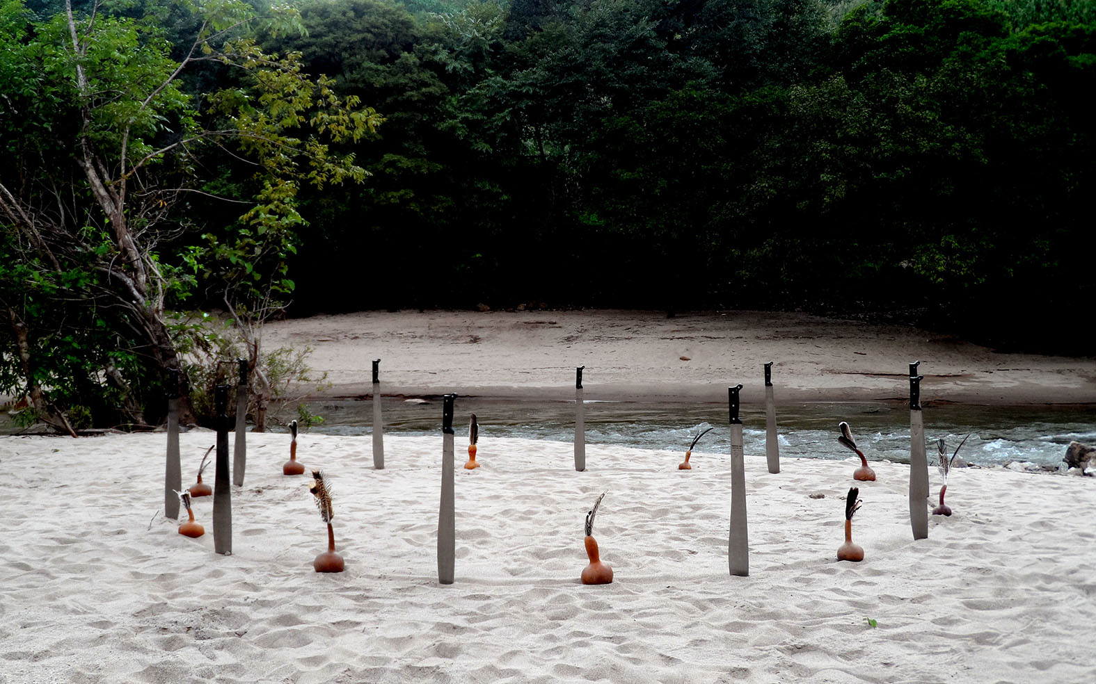Instalación ritual con machetes, jícaras y plumas sobre la arena junto al río San Pedro/Suljaa’, en Xochistlahuaca.